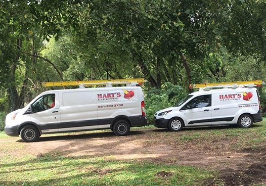 Two white Hart's Electric vans on site with ladders on top